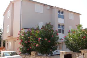 une maison blanche avec des fleurs roses devant elle dans l'établissement Apartment Potocnica 4096e, à Stara Novalja 12 autres photos