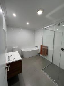 a bathroom with a tub and a sink and a shower at Waratah Holiday Home in Unanderra