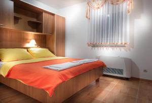 una camera da letto con un letto con lenzuola arancioni e una finestra di Apartments with a swimming pool Caska, Pag - 4109 a Novalja (Novaglia)