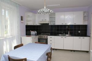 una cucina con armadi bianchi, tavolo e lampadario pendente di Apartments with parking space Vodice - 4192 a Vodice