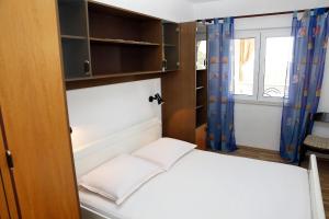 um pequeno quarto com uma cama e uma janela em Holiday apartments Vrgada, Biograd - 4200 em Vrgada