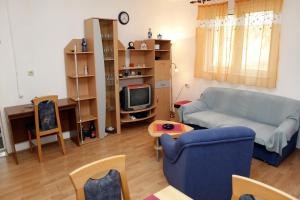 uma sala de estar com um sofá azul e uma televisão em Holiday apartments Vrgada, Biograd - 4200 em Vrgada