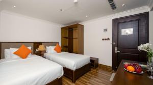 a hotel room with two beds and a bowl of fruit on a table at Roliva Hotel & Apartment Danang in Da Nang