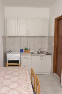 a kitchen with white cabinets and a sink and a table at Apartment Bilo 4189c in Podgreben
