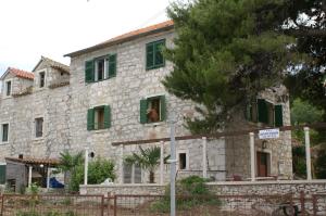 ein altes Steinhaus mit grünen Rollläden darauf in der Unterkunft Apartments by the sea Sepurine, Prvic - 4237 in Prvić Šepurine