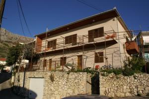 a white house with a stone wall in front of it at Apartments and rooms by the sea Sumpetar, Omis - 2099 in Jesenice