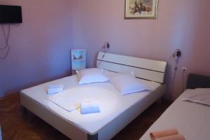 a bedroom with a white bed with two pillows at Apartments and rooms by the sea Sumpetar, Omis - 2099 in Jesenice