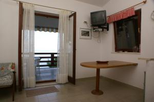 a living room with a table and a television at Apartments by the sea Nemira, Omis - 4277 in Tice