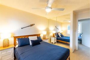 a bedroom with a blue bed and a mirror at Shoal Towers, 6 -11 Shoal Bay Rd - Air Conditiong - Wifi - Stunning water views & perfect location in Shoal Bay