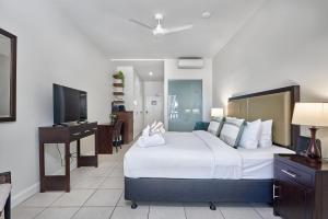 een slaapkamer met een bed, een bureau en een televisie bij Beach Club Oceanview Apartment 1221-2 Palm Cove in Palm Cove