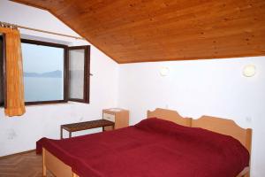 a bedroom with a red bed and a window at Rooms by the sea Sladjenovici, Dubrovnik - 2161 in Slano