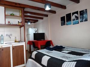 uma cozinha com uma cama, uma mesa e um frigorífico em EL MONO DE LU em San Carlos de Bariloche