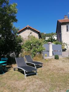 2 chaises longues assises sur l'herbe dans une cour dans l'établissement Le Garni Vendémiaire, à Vesoul