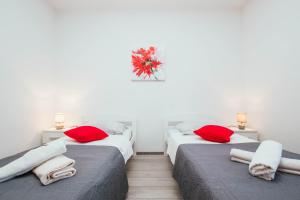 two beds in a room with red pillows on them at Apartment Arbanija 1122b in Trogir