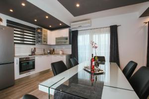 une cuisine avec une table en verre et des chaises noires dans l'établissement Apartment Arbanija 1122b, à Trogir