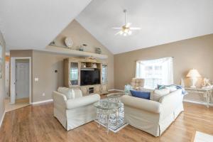 a living room with two white chairs and a tv at Seaside Sanctuary close to Navarre Beach! in Navarre