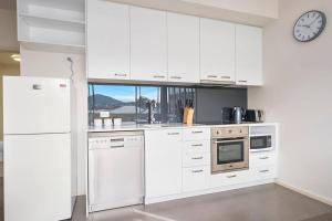 una cocina con armarios blancos y un reloj en la pared en Bellerive Quay-views walk to wharf & restaurants, en Bellerive