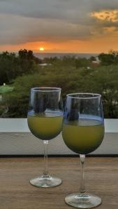 dos copas de vino sentadas en una mesa con la puesta de sol en Villa Marlyn, en Cabo Rojo