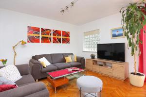 un soggiorno con divano e TV a schermo piatto di Apartments and rooms by the sea Arbanija, Ciovo - 1125 a Trogir