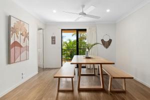 ein weißes Wohnzimmer mit einem Holztisch und einer Bank in der Unterkunft Corona St Secluded Sunshine Beach Duplex with Private Pool in Sunshine Beach