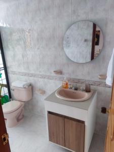 a bathroom with a sink and a toilet and a mirror at Hermosa y espaciosa casa familiar en Anapoima in Anapoima