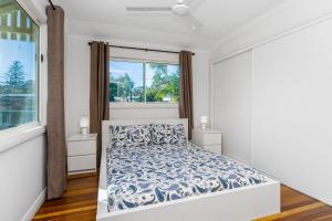 a white bedroom with a bed and a window at Bayhaven in Iluka