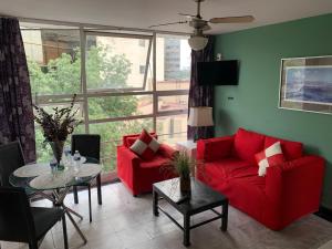 uma sala de estar com mobiliário vermelho e uma grande janela em Satya Suites & Portal San Angel Flats em Cidade do México