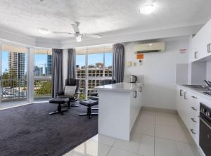 una cocina con encimeras blancas, sillas y ventanas en Surf Parade Resort, en Gold Coast