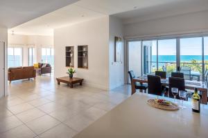 een eetkamer en een woonkamer met uitzicht op de oceaan bij Coral Cove Apartments in Bowen