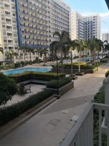 a resort with a swimming pool and a large building at Bliss by John at Sea Residences in Manila