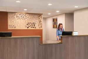 a woman standing at a counter with a laptop at Candlewood Suites Watertown Fort Drum, an IHG Hotel in Evans Mills