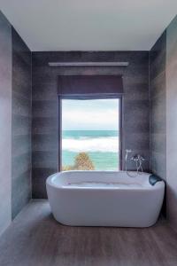 a bath tub in a bathroom with a large window at Beach & Bliss Mirissa in Mirissa