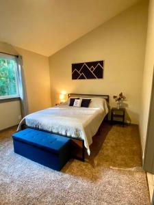 a bedroom with a large bed with a blue ottoman at NEW Modern Cabin! 5mi to Mt Rainier National Park! Hot Tub & Wifi in Ashford