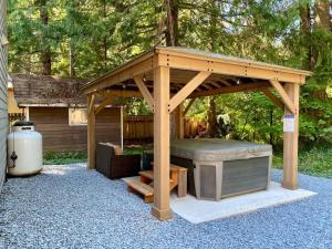 a wooden gazebo with a hot tub in a backyard at NEW Modern Cabin! 5mi to Mt Rainier National Park! Hot Tub & Wifi in Ashford