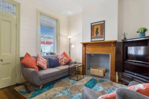 a living room with a couch and a television at Cosy Glebe Cottage - Stroll to Central Hobart in Hobart