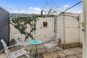 a patio with chairs and a table and a fence at Cosy Glebe cottage - walk to central Hobart in Hobart