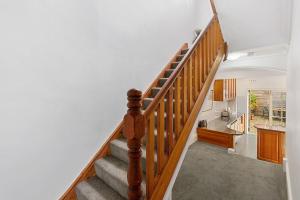 a wooden staircase in a home with a kitchen at Fabulous 2 level city pad in historic building in Hobart