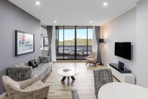 a living room with a couch and chairs and a tv at Meriton Suites Church Street, Parramatta in Sydney