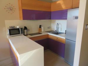 a small kitchen with purple cabinets and a refrigerator at Apartament Flores 1 in Mielno