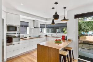 eine Küche mit weißen Schränken und einer hölzernen Arbeitsplatte in der Unterkunft Pillinger Street - luxurious renovated home in Hobart