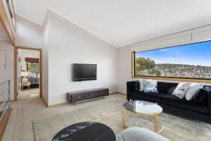 sala de estar con sofá negro y ventana grande en Panoramic water views with stunning interiors en Bellerive
