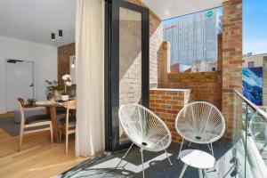 a balcony with two white chairs and a brick wall at The Retreat at Saddlers House with Private Balcony in Hobart