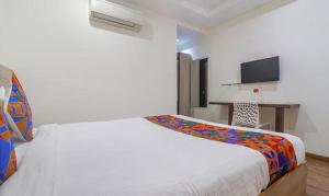 a bedroom with a large white bed and a desk at FabHotel Pride Inn Financia in Hyderabad