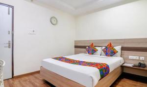 a bedroom with a large bed and a clock on the wall at FabHotel Pride Inn Financia in Hyderabad