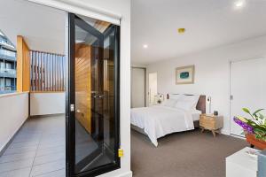 une chambre avec un lit et une porte coulissante en verre dans l'établissement Stunning Warehouse Pad - Moments from the Waterfront, à Hobart