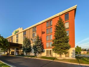 un edificio de oficinas con árboles frente a una calle en Holiday Inn Express Flint-Campus Area, an IHG Hotel, en Flint