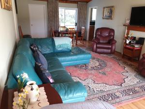 a living room with a green leather couch at Belmont Homestead in Swansea