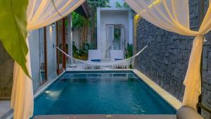 a swimming pool with a hammock in a house at Vinna Villa Seminyak in Kerobokan