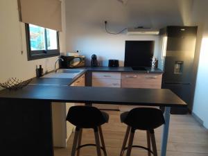 a kitchen with a black counter and two bar stools at Le coin paisible in Saint-Louis