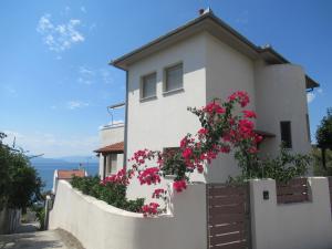 a white house with pink flowers on a fence at Seaside Boutique Villa in Volos